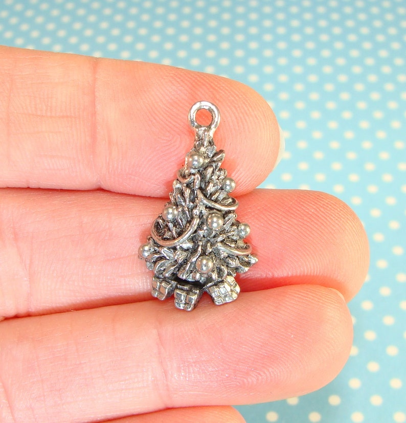 Puede incluir: Encanto de plata en forma de &aacute;rbol de Navidad con adornos y lazos.