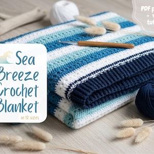 Può includere: Una coperta all'uncinetto piegata con strisce orizzontali blu navy, azzurre e bianche. Un uncinetto in legno è appoggiato sopra. Un'etichetta bianca mostra il testo Sea Breeze Crochet Blanket in 12 sizes, PDF pattern + video tutorial.