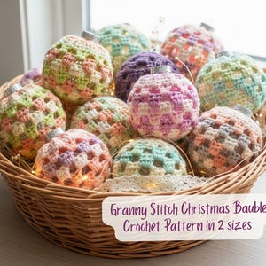 May include: A woven basket overflowing with colourful, crocheted Christmas baubles. The baubles are in shades of pink, green, purple, and peach, with silver tops. The image text reads "Granny Stitch Christmas Bauble Crochet Pattern in 2 sizes."