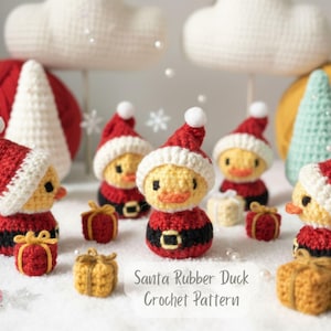 Könnte beinhalten: Gehäkelte Weihnachtsentchen mit roten und weißen Weihnachtsmützen, roten Anzügen und schwarzen Gürteln. Kleine gelbe Geschenkboxen sind um die Enten herum verstreut. Der Text "Santa Rubber Duck Crochet Pattern" ist sichtbar.