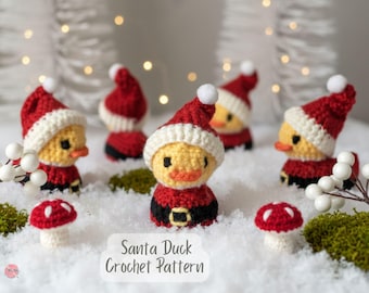 May include: Crocheted Santa Duck figurines with yellow bodies, red Santa hats, and black belts. The ducks are arranged on a snowy surface with small red and white mushroom decorations. The text "Santa Duck Crochet Pattern" is visible.