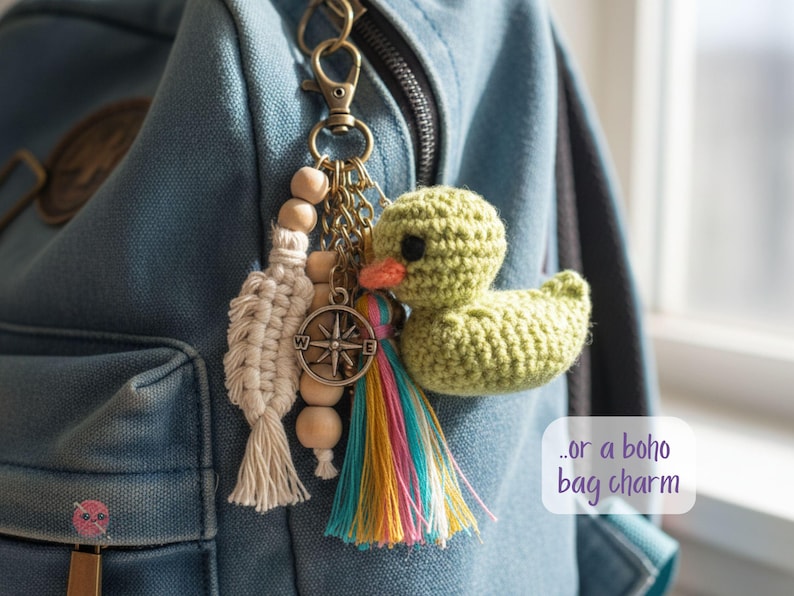 Pu&ograve; includere: Un portachiavi fatto a mano con un'anatra verde all'uncinetto, una nappa colorata, perline di legno e un ciondolo a forma di bussola. Il ciondolo &egrave; attaccato a uno zaino di jeans con un fermaglio di metallo.