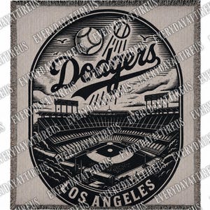 May include: A beige and black woven throw blanket featuring a detailed illustration of a baseball stadium with the text "Dodgers Los Angeles". The design includes baseballs, stadium elements, and the team's logo.