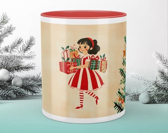 May include: A ceramic mug with a red interior and rim, featuring a vintage illustration of a girl in a red and white striped dress carrying Christmas gifts. The mug has a cream-colored background with a Christmas tree design and the text "Twinkle & Twist".