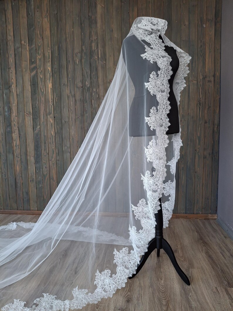 May include: A white bridal veil with a delicate lace trim. The veil is long and flowing, with a scalloped edge.