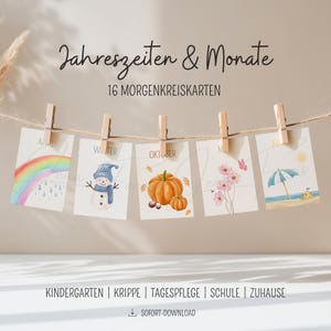 Könnte beinhalten: Eine Reihe von Karten mit Aquarellillustrationen zu saisonalen Themen, darunter ein Regenbogen, ein Schneemann, Kürbisse, Blumen und eine Strandszene. Die Karten werden mit Holzklammern an einer Schnur befestigt. Der Text enthält die Monate und die Worte "Jahreszeiten & Monate".