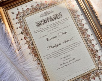Puede incluir: Un certificado de matrimonio islámico enmarcado con bordes florales dorados y rojos, caligrafía árabe y texto en inglés que nombra a Usman Khan y Khadejah Ahmed. Una pluma blanca descansa en diagonal en la esquina inferior izquierda.
