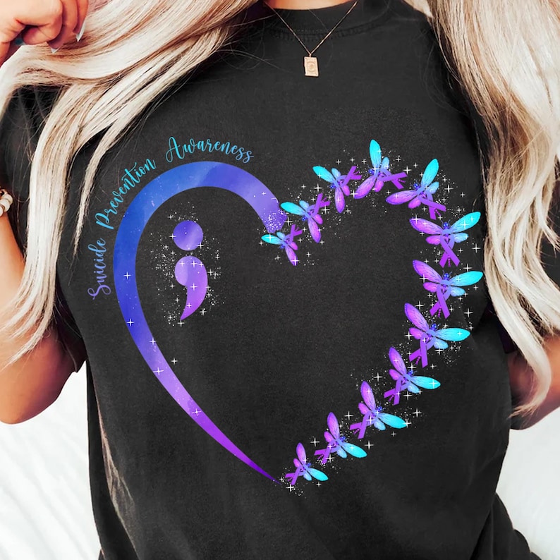 a woman with blonde hair wearing a black shirt with a heart and butterflies on it