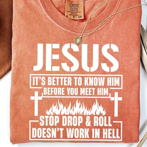 May include: A burnt orange t-shirt with a white graphic that reads "JESUS IT'S BETTER TO KNOW HIM BEFORE YOU MEET HIM -STOP DROP & ROLL DOESN'T WORK IN HELL-"