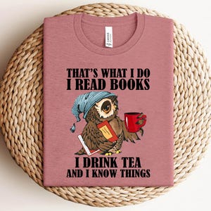 May include: A pink t-shirt with a cartoon owl wearing a blue sleep mask and holding a book and a cup of tea. The text on the shirt reads "That's what I do I read books I drink tea and I know things."