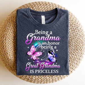 May include: A dark blue t-shirt with the text "Being a Grandma is an honor being a Great Grandma IS PRICELESS" in white. Two butterflies, one pink and one blue, are on either side of the text.