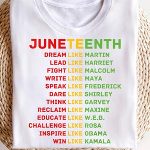 Peut inclure: T-shirt blanc avec le mot "JUNETEENTH" en rouge, jaune et vert. En dessous, des phrases comme "DREAM LIKE MARTIN" et "LEAD LIKE HARRIET" sont imprimées en différentes couleurs. Le t-shirt est en matière souple.