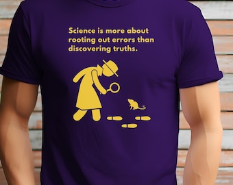 Op de afbeelding: Paars T-shirt met een gele afbeelding van een persoon met een vergrootglas die naar een muis met voetafdrukken kijkt. De tekst op het shirt luidt "Wetenschap gaat meer over het uitroeien van fouten dan over het ontdekken van waarheden."