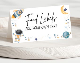 May include: White tent card with the words "Food Labels" and "Add Your Own Text" in black script. The card is decorated with watercolor illustrations of a rocket, astronaut, moon, stars, and a planet.