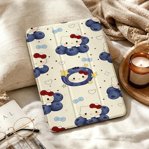 Könnte beinhalten: Eine rechteckige Tablet-Hülle mit cremefarbenem Hintergrund und einem wiederkehrenden Muster aus Hello Kitty-Figuren, dunkelblauen Blaubeeren, kleinen hellblauen Schleifen, gelben Sternen, braunen Punkten und weißen Herzumrissen.