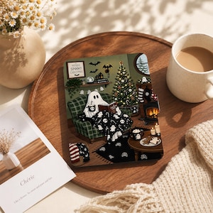 Könnte beinhalten: Ein rechteckiger Untersetzer mit einer festlichen Illustration eines Geistes, der in einem grün karierten Sessel sitzt und neben einem Weihnachtsbaum ein Buch liest. Das Bild zeigt einen Kamin, Strümpfe, eine schwarze Katze und den Text Merry Spooky Christmas.