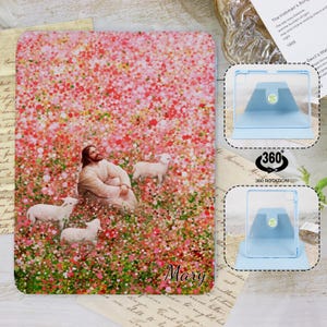 Peut inclure: Une coque de tablette avec une scène pastorale représentant une figure et des moutons dans un champ de fleurs roses et rouges. Le nom "Mary" est écrit en cursive. Un support de tablette bleu est également présenté.