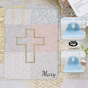 Peut inclure: Une coque de tablette bleu clair avec un motif floral et un motif de croix dorée. La coque est dotée d'un support intégré et d'une fonction de rotation à 360 degrés. Le nom "Mary" est imprimé sur la coque.