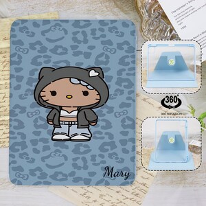 Könnte beinhalten: Eine hellblaue Tablet-Hülle mit einer Cartoonfigur in einem grauen Kapuzenpullover, einem weißen Oberteil und einer blauen Jeans. Die Hülle hat ein Leopardenmuster und den Namen "Mary". Enthält einen um 360 Grad drehbaren Tablet-Ständer.