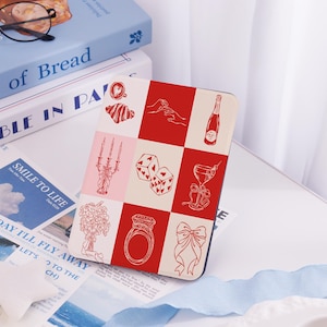 Könnte beinhalten: Eine rot-weiß karierte Kindle-Hülle mit verschiedenen Illustrationen in Rot, darunter eine Champagnerflasche, ein Ring, eine Schleife, Würfel, ein Cocktailglas, ein Kerzenleuchter, ein Croissant und eine Kaffeetasse.