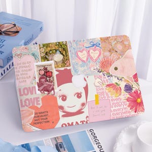 May include: A decorative laptop case featuring a collage of images, including a pink fish, flowers, hearts, and the words "LOVE" and "OMATE." The case has a mix of pastel colors and a whimsical design.