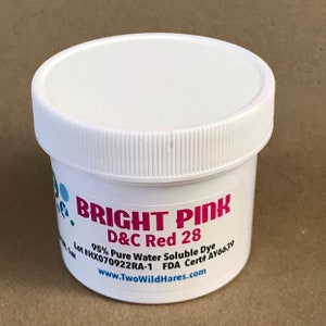 May include: A white plastic jar with a pink label that reads "BRIGHT PINK D&C Red 28 95% Pure Water Soluble Dye Lot #HX070922RA-1 FDA Cert# AY6639 www.TwoWildHares.com"