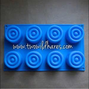 May include: Blue silicone mold with eight circular cavities, each with concentric rings. The mold is designed for making soap or other crafts.