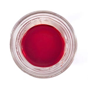 May include: A clear glass jar with a red liquid inside. The jar has a wide mouth and a smooth rim.