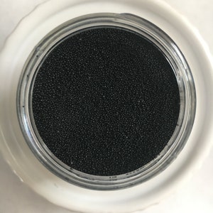 May include: A clear glass jar filled with small black beads.