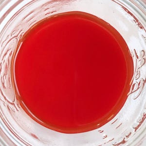 May include: A glass jar filled with a bright red liquid.