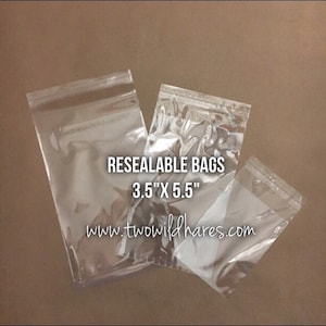 May include: Three clear plastic resealable bags with a zipper closure. The bags are different sizes. The largest bag has the text "Resealable Bags 3.5" x 5.5" www.twowildhares.com" printed on it.