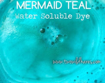 May include: Close-up of a teal blue liquid with bubbles. The text "MERMAID TEAL Water Soluble Dye" is written in white on top of the liquid. The website address "www.twowildhares.com" is written in white at the bottom of the image.
