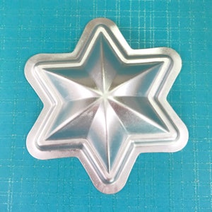 May include: A silver metal star-shaped mold for baking or making crafts.
