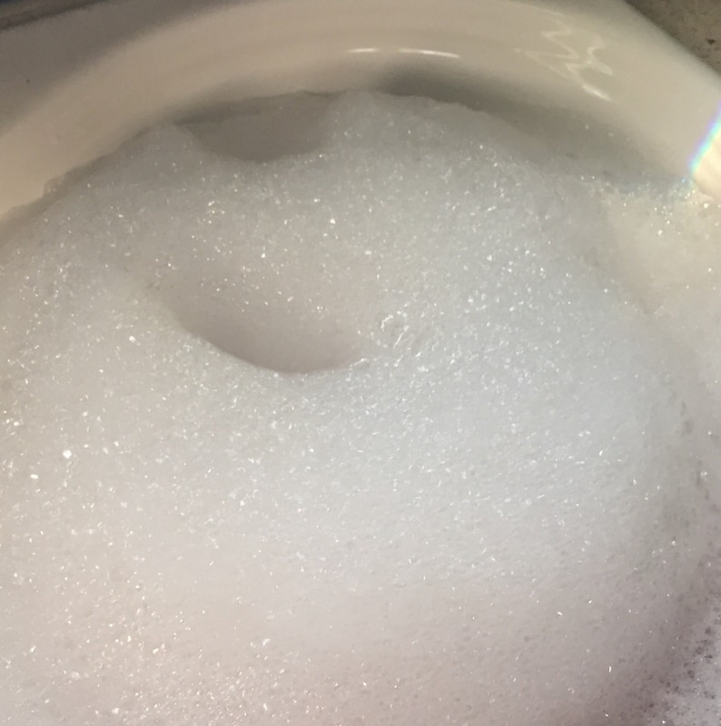 Puede incluir: Primer plano de un inodoro de porcelana blanca lleno de burbujas blancas y espumosas.