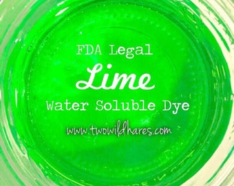 May include: A close-up of a jar of green water-soluble dye. The label reads "FDA Legal Lime Water Soluble Dye" and "www.twowildhares.com".
