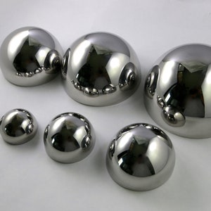 May include: A set of six shiny, silver, hemispherical metal bowls of varying sizes. The bowls are arranged in a row from largest to smallest.