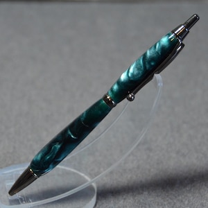 May include: A teal and silver pen with a marbled design. The pen is on a clear plastic stand.