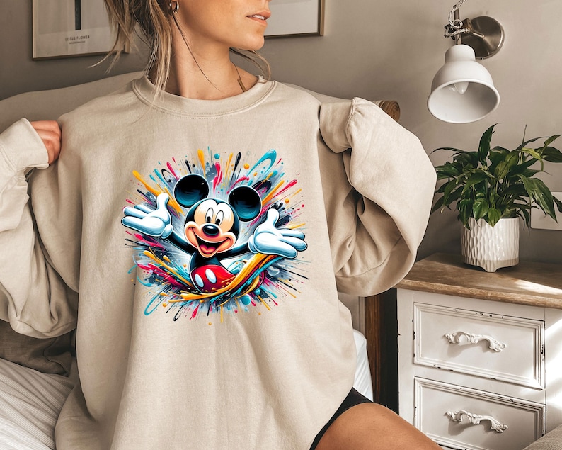 a woman wearing a sweatshirt with a mickey mouse graphic on it