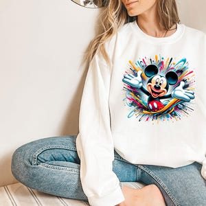 a woman sitting on the floor wearing a mickey mouse shirt