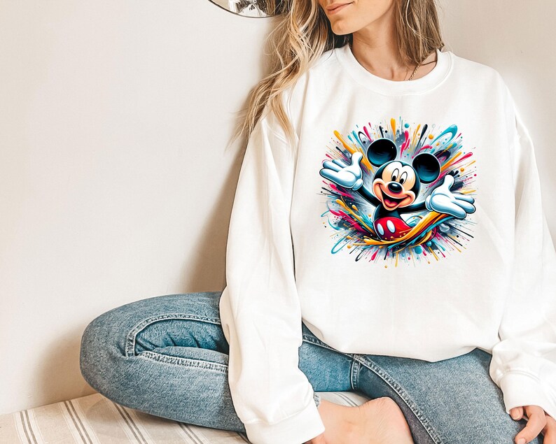 a woman sitting on the floor wearing a mickey mouse shirt