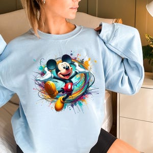 a woman wearing a blue sweatshirt with mickey mouse on it