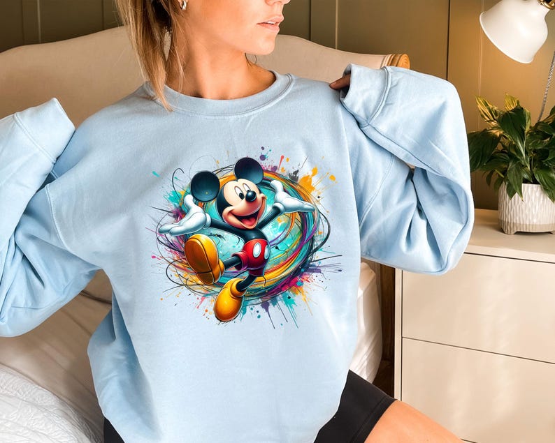 a woman wearing a blue sweatshirt with mickey mouse on it