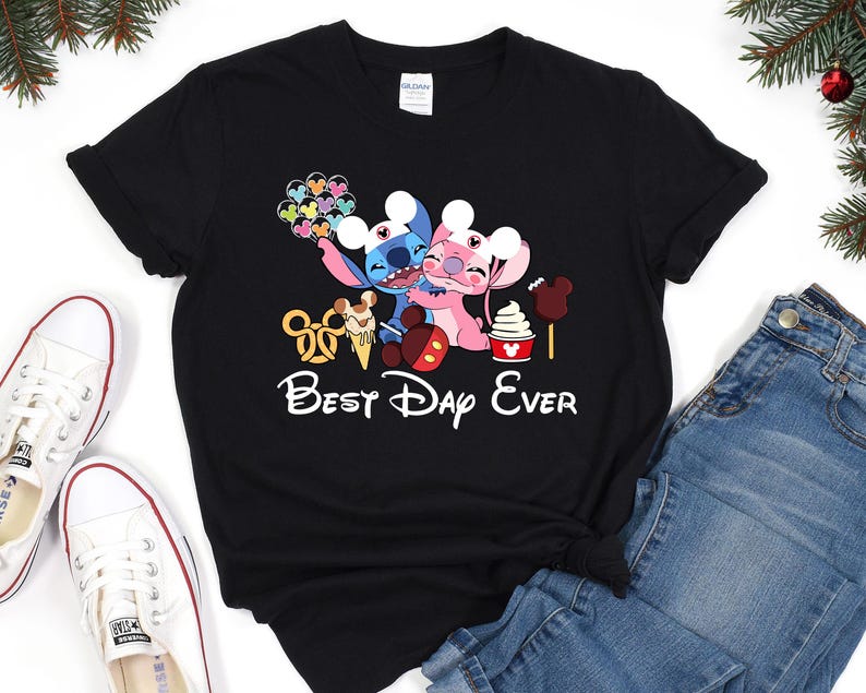 A black t-shirt with a Disney-themed graphic design, including characters from the Disney movie Lilo & Stitch, along with various Disney-related items such as a Mickey Mouse ear, a hot dog, and a cone. The text "Best Day Ever" is also present on the t-shirt.
