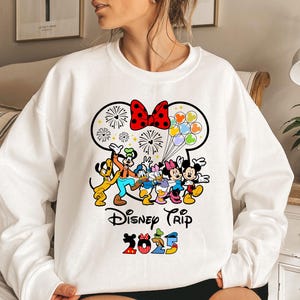 a woman wearing a white sweatshirt with mickey mouse and friends on it