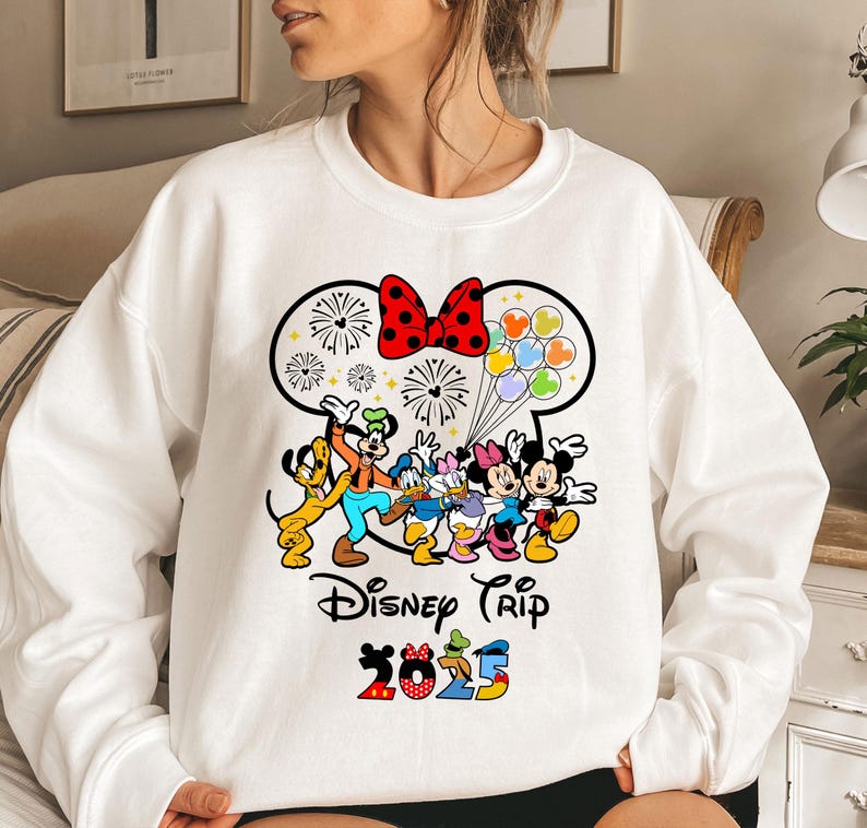 a woman wearing a white sweatshirt with mickey mouse and friends on it