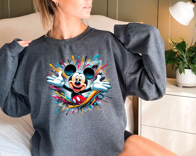 a woman wearing a sweatshirt with a mickey mouse graphic on it