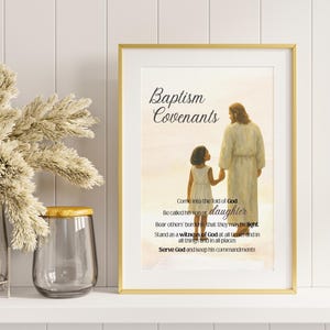 May include: A framed print with gold trim featuring an illustration of Jesus and a young girl. The text "Baptism Covenants" is at the top, with additional text below. The background is a soft, warm color.