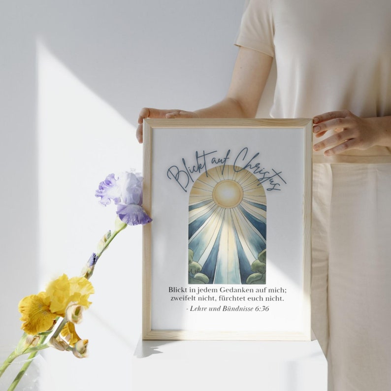 May include: A framed print with a watercolor illustration of a sun shining through a blue and white archway. The text "Blickt auf Christus" is written in blue cursive script above the archway. The text below the archway reads "Blickt in jedem Gedanken auf mich; zweifelt nicht, f&uuml;rchtet euch nicht. - Lehre und B&uuml;ndnisse 6:36"