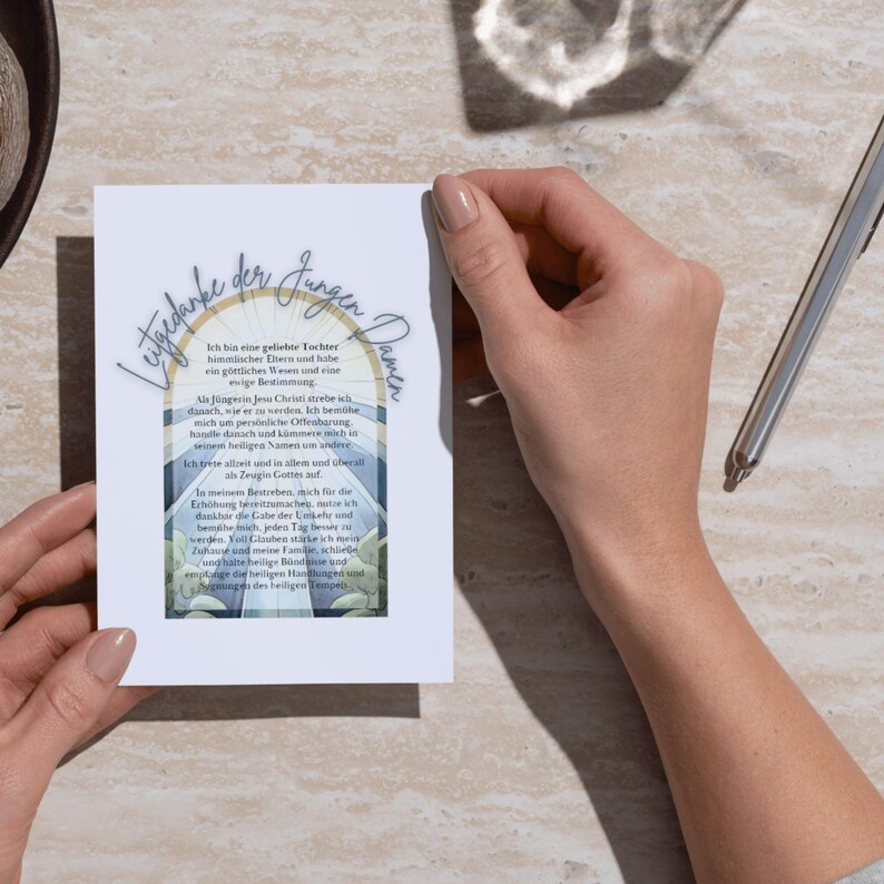 May include: A white card with a blue and white stained glass design. The card has a quote in German that reads "Letztdanke der Jungen Damen" and "Ich bin eine geliebte Tochter himmlischer Eltern und habe ein g&ouml;ttliches Wesen und eine ewige Bestimmung. Als J&uuml;ngerin Jesu Christi strebe ich danach, war er zu werden. Ich bem&uuml;he mich um pers&ouml;nliche Offenbarung, handle danach und komme mehr in seinen heiligen Namen um andere. Ich trete allzeit und in allen und &uuml;berall als Zeugin Gottes an. In meinem Bestreben, mich f&uuml;r die Erh&ouml;hung bereitzumachen, danke ich f&uuml;r die Gabe der Umkehr, bem&uuml;he mich jeden Tag f&uuml;r Zuhause und meine Familie, schreibe und halte heilige B&uuml;ndnisse und erzeuge der heiligen Handlung und erlange der heiligen Tempel."