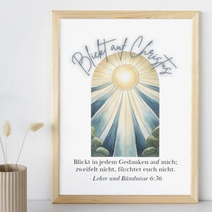 May include: A framed print with a watercolor illustration of a sun shining through clouds. The text "Blickt auf Christus" is written in blue cursive at the top of the image. The text "Blickt in jedem Gedanken auf mich; zweifelt nicht, f&uuml;rchtet euch nicht. - Lehre und B&uuml;ndnisse 6:36" is written in black at the bottom of the image.